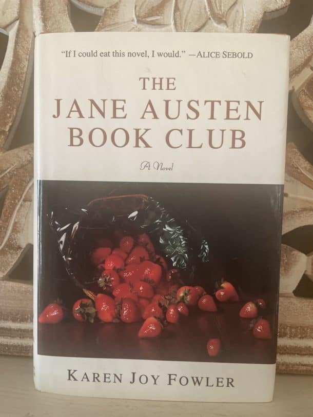 Picture of a hardcover version of the book "The Jane Austen Book Club" by Karen Joy Fowler featuring a white background and a spilled basket of strawberries